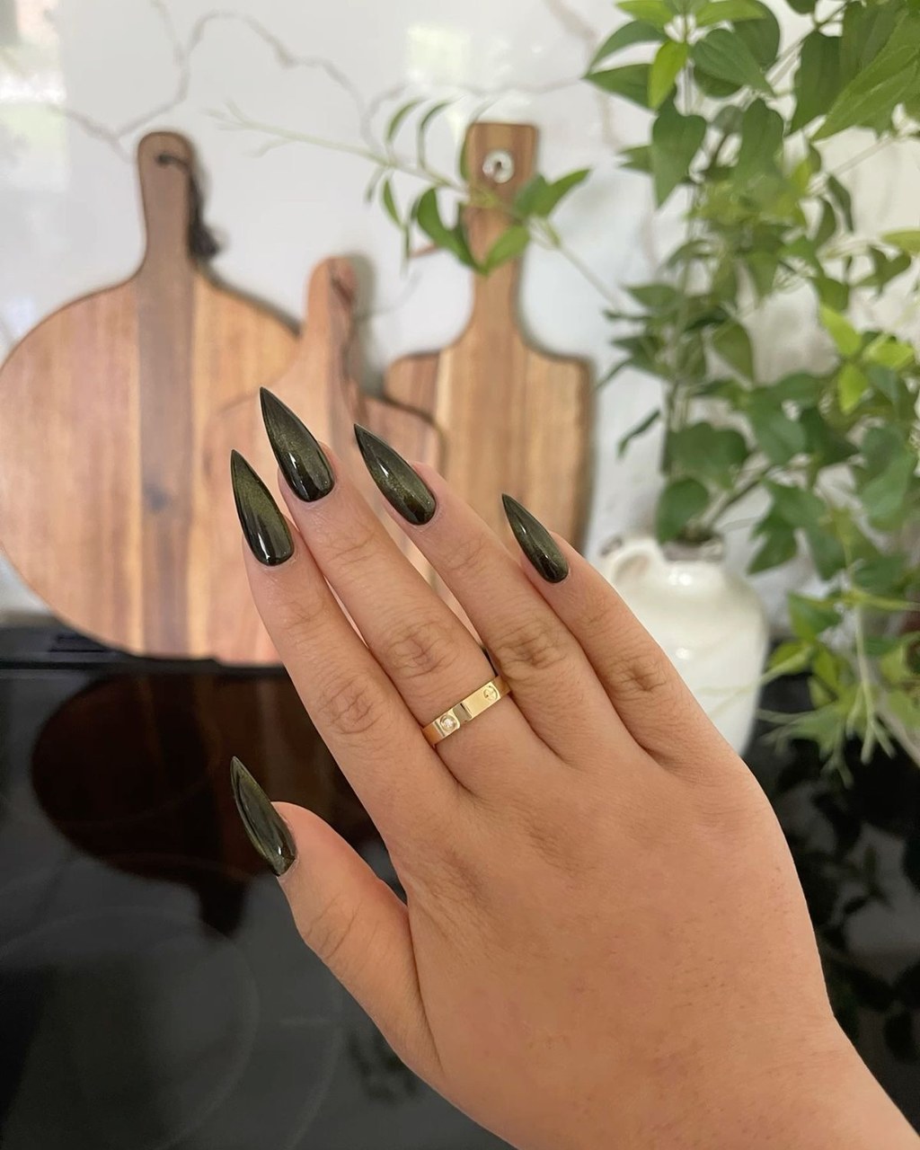 Glossy dark olive stiletto nails with gold shimmer